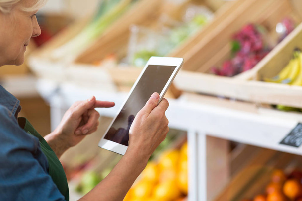 Shop assistant with digital tablet in small grocery store - Foto, afbeelding