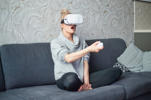 Молода жінка дивиться відео або грає з VR окулярами на голові
 - Фото, зображення