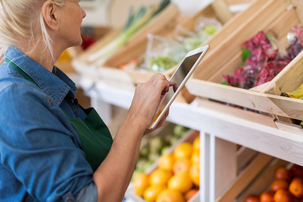 Shop assistant with digital tablet in small grocery store - Photo, Image