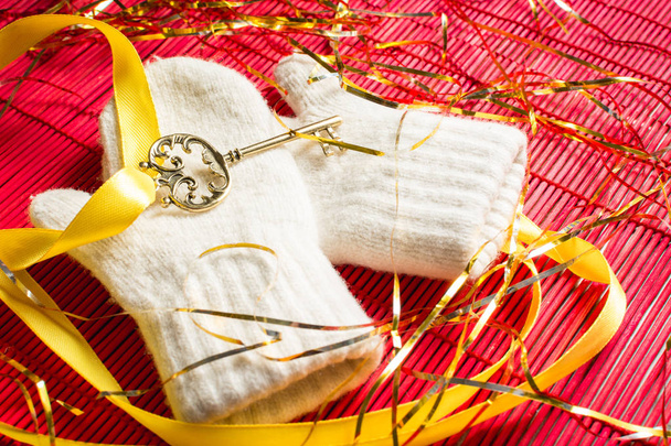 Golden key with yellow tape lying on the new year's baby mittens. - Zdjęcie, obraz