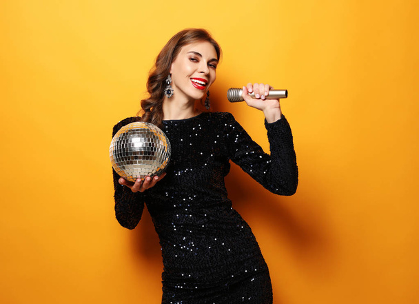 woman in evening dress holding microphone and disco ball - Fotoğraf, Görsel