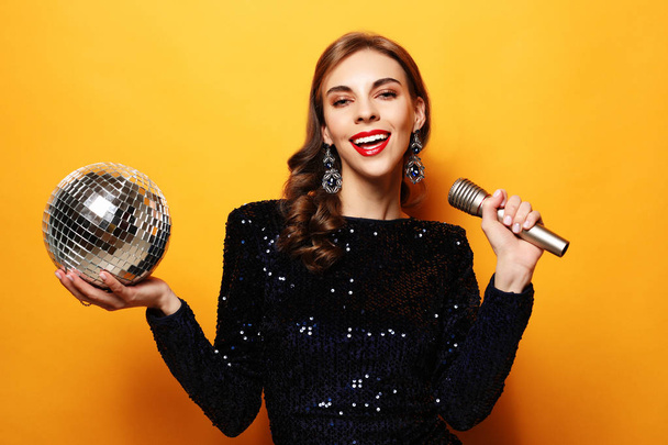 woman in evening dress holding microphone and disco ball - Foto, immagini