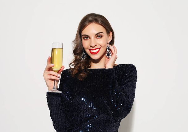 beautiful girl in a cocktail dress with evening make-up and curls holding a glass of champagne - Foto, imagen
