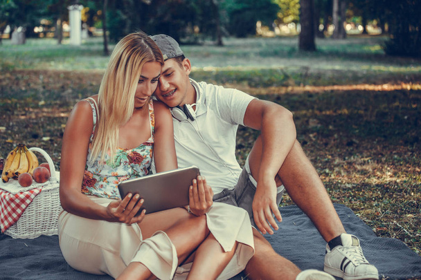schönes junges Paar mit digitalem Tablet beim Picknick in der - Foto, Bild