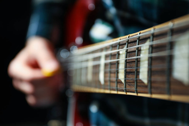 Άνθρωπος παίζει σε ηλεκτρική κιθάρα με σκούρο φόντο, κοντινό πλάνο - Φωτογραφία, εικόνα