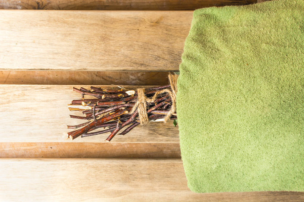 Birch broom lies under a green towel in a bath - Foto, Imagem