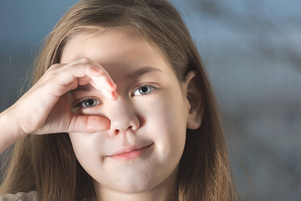 Beautiful child looks to the eye through the hand - Φωτογραφία, εικόνα