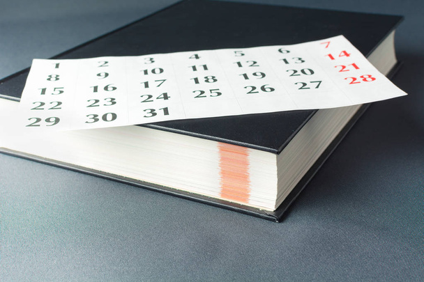 La page blanche du calendrier se trouve sur un livre épais noir
 - Photo, image