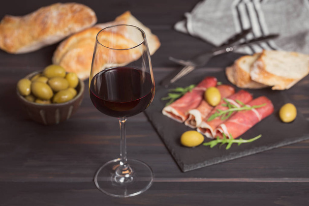 Glass of red wine with slices of cured ham or Spanish jamon serr - Fotó, kép