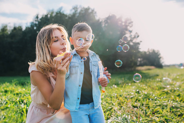 Mother and little son blowing soap bubbles outdoor - Photo, Image