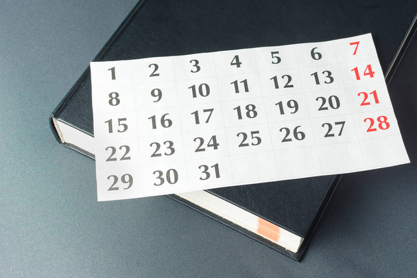 Kalenterin valkoinen sivu on mustalla paksulla kirjalla
 - Valokuva, kuva