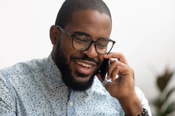 Hymyilevä afrikkalainen amerikkalainen liikemies puhuu älypuhelimella ota yhteyttä asiakkaaseen
 - Valokuva, kuva