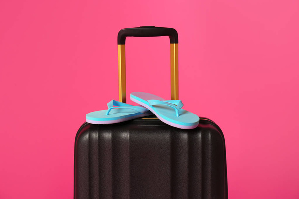 Stylish suitcase with flip flops on color background - Photo, image