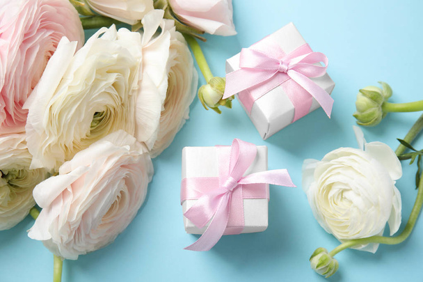 Beautiful ranunculus flowers and gift boxes on color background, view from above - 写真・画像