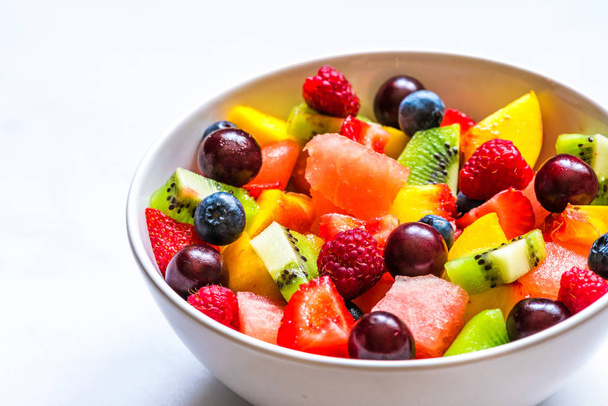 μπολ με φρούτα του καλοκαιριού και σαλάτα μούρων σε λευκό μαρμάρινο φόντο. υγιεινό φαγητό για χορτοφάγους - Φωτογραφία, εικόνα