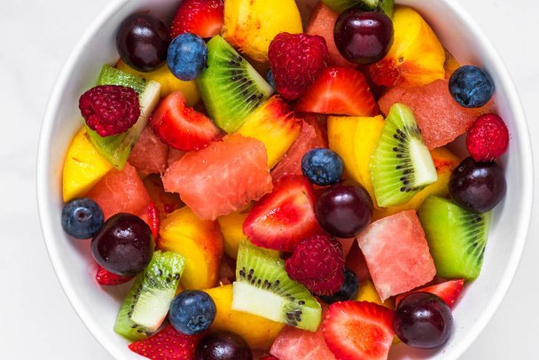 фруктовый салат с арбузом, клубникой, вишней, черникой, киви, малиной и персиками в миске. здоровое веганское питание
 - Фото, изображение