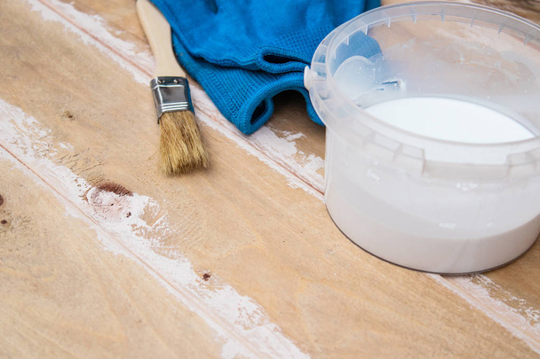 Кисть краски с банкой краски и перчатками на деревянных досках. Подготовка к покраске
 - Фото, изображение
