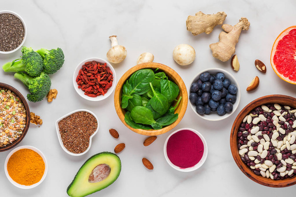 白い大理石のテーブルの上のスーパーフード。野菜、アサイ、ウコン、果物、ベリー、ナッツや種子。健康食品 - 写真・画像