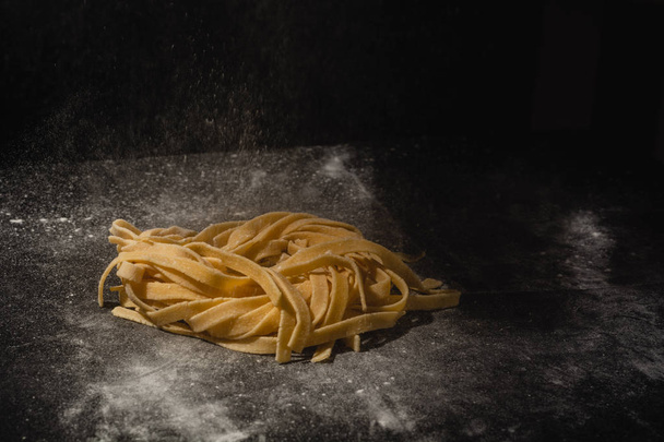 Fresh italian uncooked homemade pasta. Hands making pasta. Spaghetti. Fresh italian spaghetti. Closeup of process of making cooking homemade pasta. Chef make fresh italian traditional pasta - Photo, Image