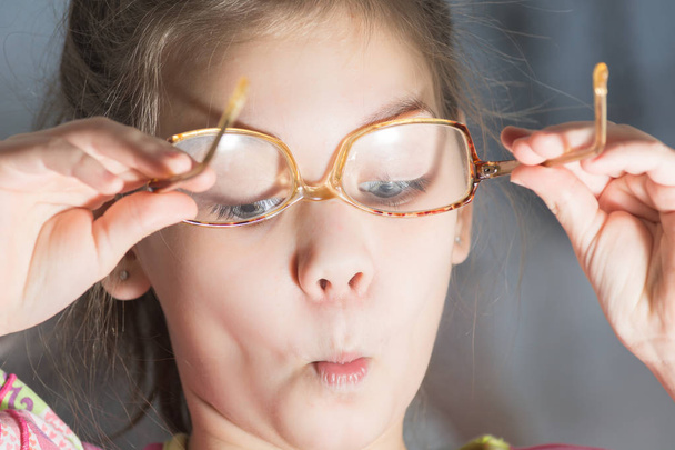 Beautiful child is trying on glasses to face - Φωτογραφία, εικόνα