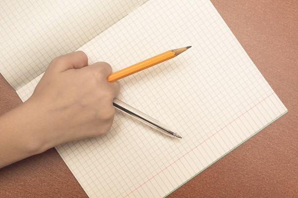 The hand of a schoolgirl holding pencil and pen. - Φωτογραφία, εικόνα