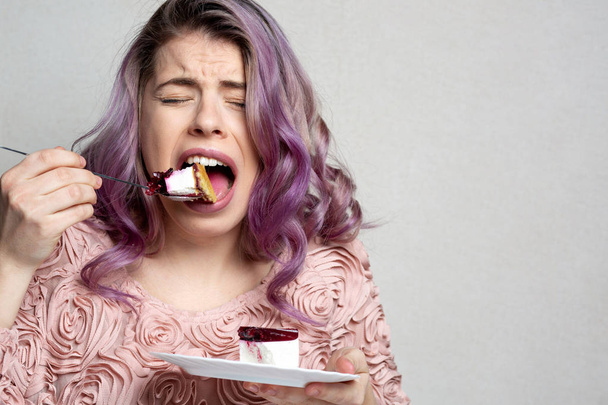 Upset young model eating palatable cake with berries. Space for  - 写真・画像