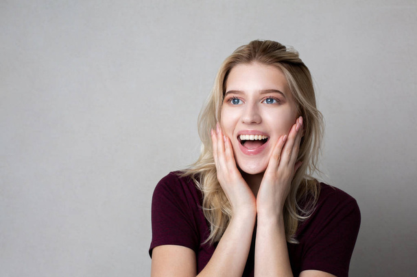 Excited blonde woman with natural makeup posing against grey bac - Foto, afbeelding
