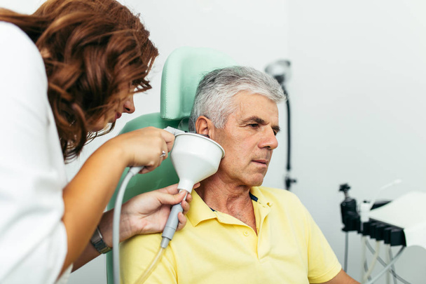 Senior man at medical examination or checkup in otolaryngologist's office. Ear irrigation and earwax removal.  - Foto, imagen