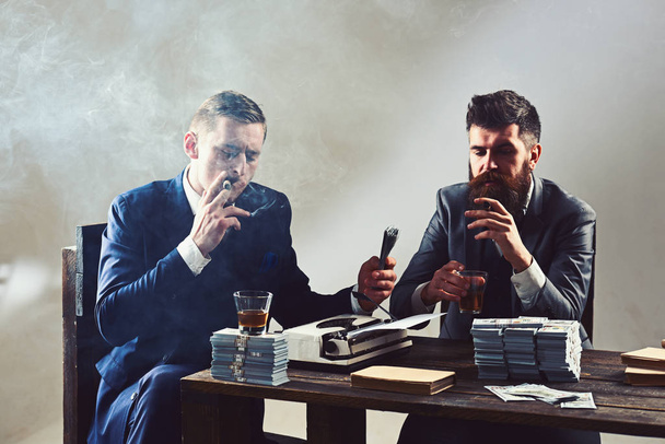 Celebrating success. Successful investment in business. Business partners with cash money. Businessmen write financial report while drinking and smoking. Money brokers counting profit increase - 写真・画像