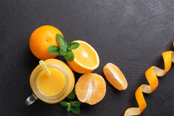 A group of oranges and a jar of juice on a dark background. - 写真・画像