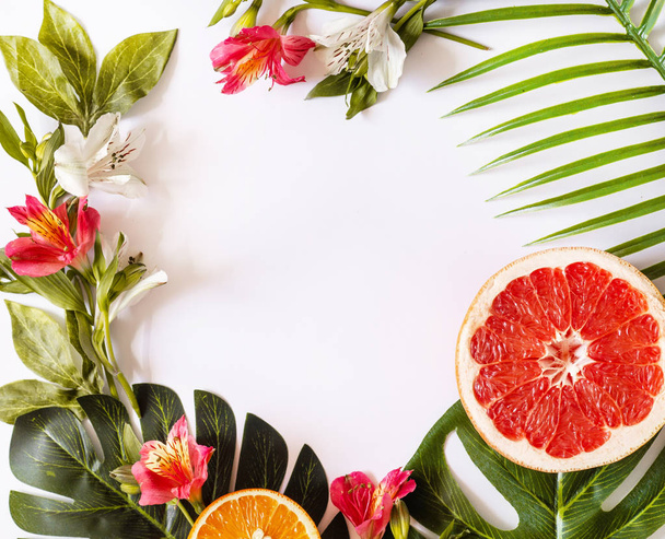 Letní tropický motiv nebo šablona s prostorem pro text, různé ovoce, zelené listy a květiny - Fotografie, Obrázek