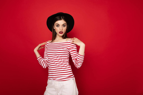 Surprised girl in striped blouse and black hat - Fotoğraf, Görsel