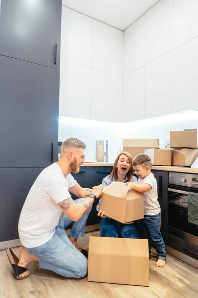 Young family unpacking boxes in new home - Foto, afbeelding
