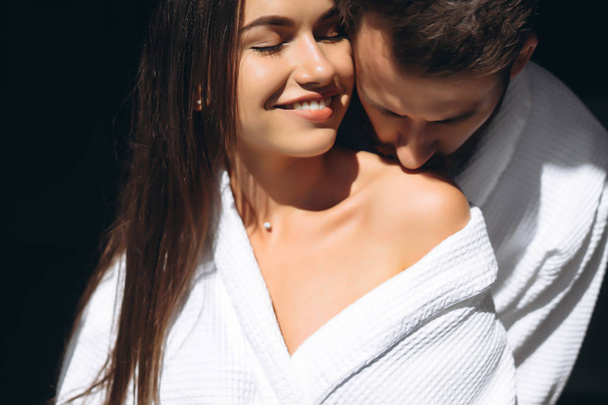 Young man gently kissing beautiful woman on shoulder - Фото, изображение