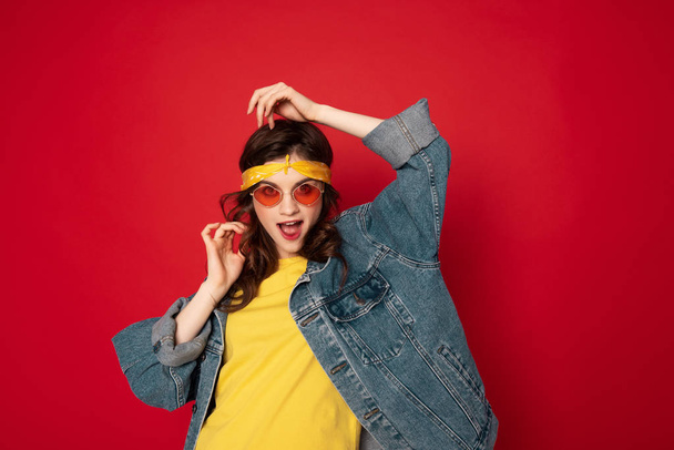 Coquettish hipster girl posing isolated on red - Foto, Imagen