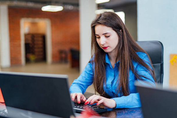 Professional young woman computer engineer using code language development on the blurred office background. Pretty female typing on a computer. Website design - 写真・画像