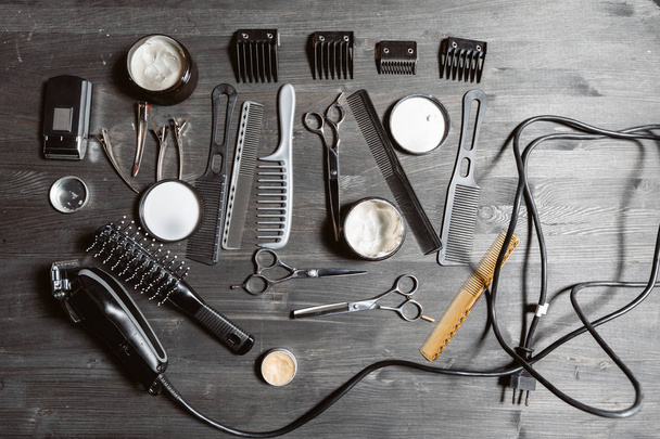Set professioneller Friseurwerkzeuge auf grauem Hintergrund. Holztisch im Friseurladen. Arbeitswerkzeug des Friseurmeisters - Foto, Bild