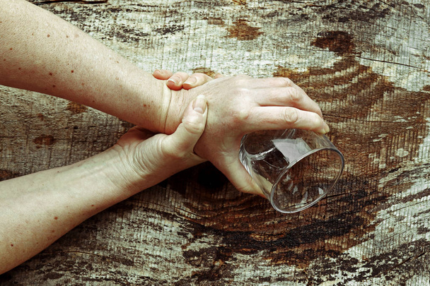 Parkinson hastası bir kadın ellerini o kadar kötü titriyor ki artık bardağı tutamıyor. Yaşlı bir kadının güçlü bir şekilde titreyen elleri - Fotoğraf, Görsel