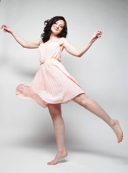 young woman with curly hair wearing pink dress - 写真・画像