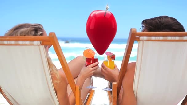 Digital composite of caucasian couple by the beach celebrating with a toast while a heart floats between them - Filmagem, Vídeo