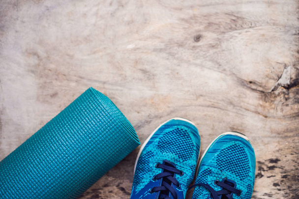 Everything for sports turquoise, blue shades on a wooden background. Yoga mat, sport shoes sportswear and bottle of water. Concept healthy lifestyle, sport and diet. Sport equipment. Copy space - Foto, Bild