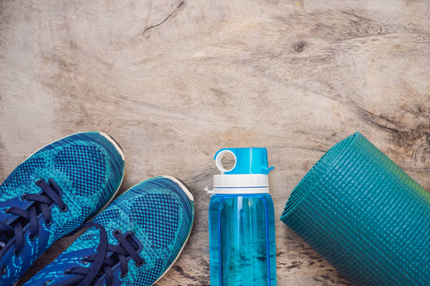 Everything for sports turquoise, blue shades on a wooden background. Yoga mat, sport shoes sportswear and bottle of water. Concept healthy lifestyle, sport and diet. Sport equipment. Copy space - Foto, Imagen