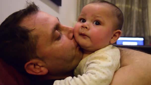 Der sechs Monate alte Junge und sein Vater genießen die gemeinsame Zeit. Vater und Sohn kuscheln - Filmmaterial, Video