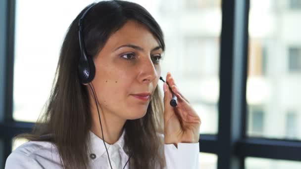 4K. Call Center pracy. Kobieta operator w słuchawkach odpowiedzieć klientowi w biurze - Materiał filmowy, wideo