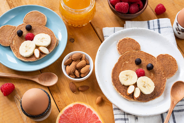 Crianças café da manhã com panquecas e frutas em uma mesa de madeira
 - Foto, Imagem