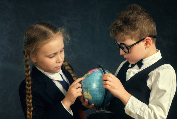 Los estudiantes de primaria consideran el mundo. Concepto de educación
 - Foto, Imagen