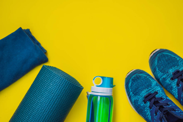 Everything for sports turquoise, blue shades on a yellow background. Yoga mat, sport shoes sportswear and bottle of water. Concept healthy lifestyle, sport and diet. Sport equipment. Copy space - Foto, Bild