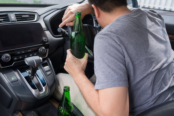 Ne buvez pas pour conduire concept, jeune homme ivre boire une bouteille de bière ou d'alcool pendant la conduite de la voiture dangereusement
. - Photo, image