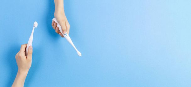 Manos de niño con cepillos de dientes eléctricos sobre fondo azul
 - Foto, Imagen