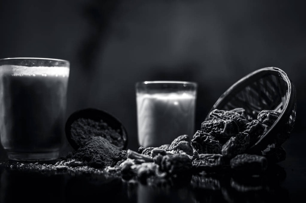 Close up of popular Indian and asian Winter drink on wooden surface i.e. Kharek ka dudh or dried dates milk consisting of milk,dried dates,cashews,almonds dry fruits and sugar. Black and white - Valokuva, kuva